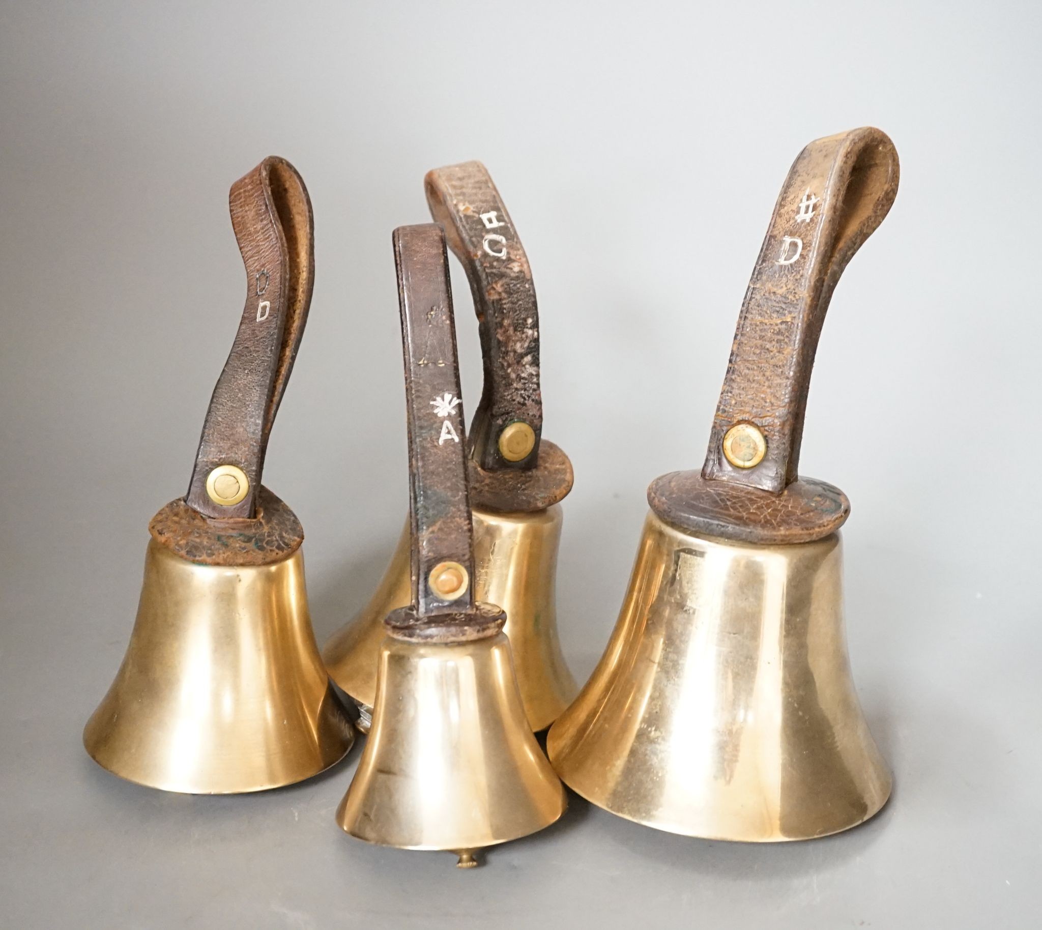 A rare set of 32 Whitechapel musical handbells, full chromatic scale, circa 1900, largest 23cm, including leather strap.